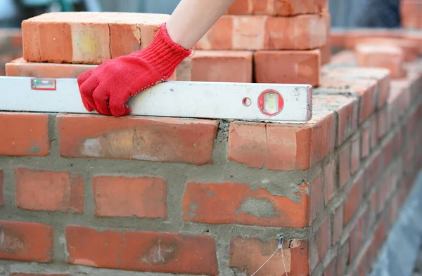 Spirit Levels for Bricklaying. Bricklayer Girl Hand Using a Spirit Level to Check Bricklaying Foundation Wall Outdoors.