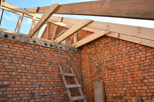 Brick house attic rootop under construction with frame of wooden beams, trusses, eaves — Stock fotografie