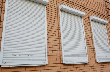 Korunmak için camlarında metal jaluzili tuğla ev.