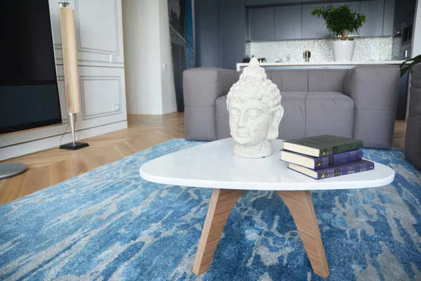 QUIIV, UCRÂNIA - 28 de janeiro de 2020: Estátua de Buda na mini mesa com livros em apartamento de luxo — Fotografia de Stock