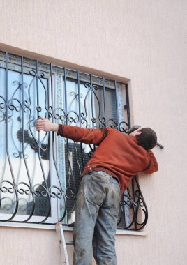 KYIV, UKRAINE - March, 16, 2020:  The man is installing steel security gates on the window. Window safety metal gates or window grill protects house from robbery.