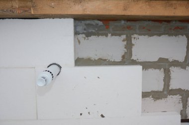 Sert polistiren köpük tahta yalıtım malzemesi yapıştırıcı ya da yapıştırıcıyla havalandırma borusuyla tuğla bir duvara yerleştiriliyor..  