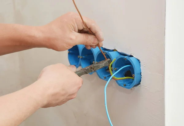 A building contractor is installing a new multi electrical outlet, connecting wires, cables in plastic isolation box.