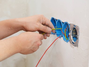Bir elektrikçi bağlantı kutusuna kabloları, kabloları ve kabloyu kuran yeni bir çoklu priz takıyor..