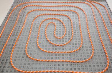 Radyasyonlu sıcak su döşeme ısıtma sistemi kuruluyor. Ev tadilatı sırasında boruyu yalıtım katmanına döşüyorlar..