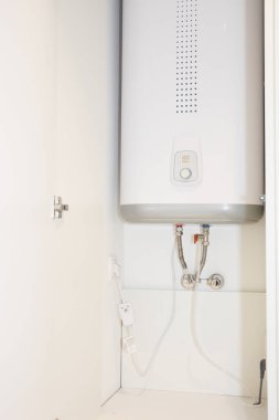Su kazanı nasıl saklanır: bir dolaba yerleştirilmiş beyaz su ısıtıcısı, banyoda dolap, mutfakta.