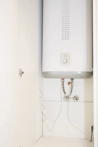 How to hide water boiler: white water heater installed in a cabinet, cupboard in bathroom, kitchen.