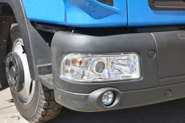 Taksi, tekerlek ve ön siyah tampon, far, park sensörleri ve mavi bir kamyonun sis önleyici ışıkları..