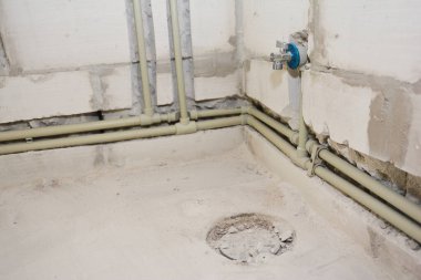 Banyo tesisat sisteminde yakın plan, su şebekesi, drenaj boruları ve havalandırma borularından oluşan havalandırma bacası gizli otoklaz beton blok duvarı..