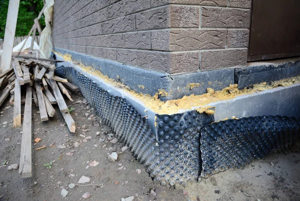 Installing dimpled membrane, drainage sheet, vapor barrier for waterproofing and drainage, sealed with foam on the exterior poured concrete wall foundation, basement. — Stock Image Installing Dimpled Membrane Drainage Sheet Vapor Barrier Waterproofing Drainage Sealed Stock Image