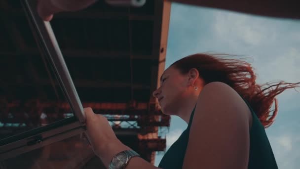 Mann helfen Mädchen mit rotem Haar in türkisfarbenem Kleid Motorboot fahren. Romantisch. Brücke — Stockvideo
