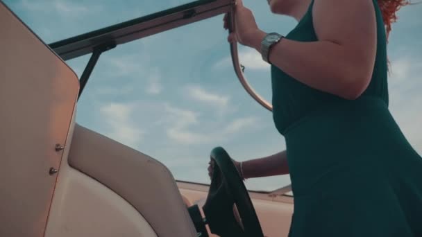 Capelli rossi ragazza in abito guida barca a motore. Serata estiva. Tramonto. Vento . — Video Stock