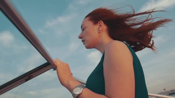 Junges Mädchen mit rotem Haar auf einem Motorboot. Sommerwindiger Abend. Sonnenuntergang. blauer Himmel. — Stockvideo