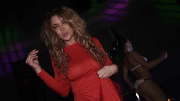 Meisje in de rode jurk dansen op stand op party in discotheek. Wave handen. Borst. — Stockvideo