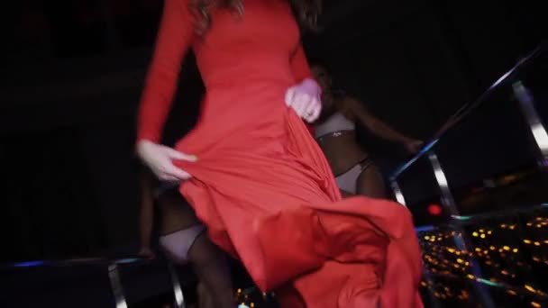 Girl in red dress dance on stand on party in nightclub. Go go girls in bikini. — Stock Video