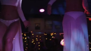 Git kız beyaz bikini dans gece kulübünde stand gidin. Yüksek topuklu ayakkabılar. Dalga kalça