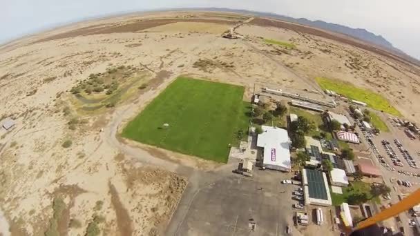 Parašutista s padákem na obloze nad písky z Arizony. Přistání na zelené louce. — Stock video