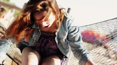 Mutlu kız kamera hamak beach gülümseme üzerinde oturuyor. Güneşli bir gün. Kaygısız