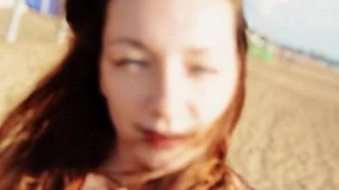 Genç kız plajda çiçek ile kamera bak. Güneşli bir gün. Kaygısız. İnsanlar.