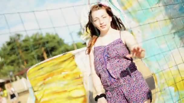 Щаслива молода дівчина з квіткою у волоссі на волейбольній сітці на пляжі посмішка в камері . — стокове відео