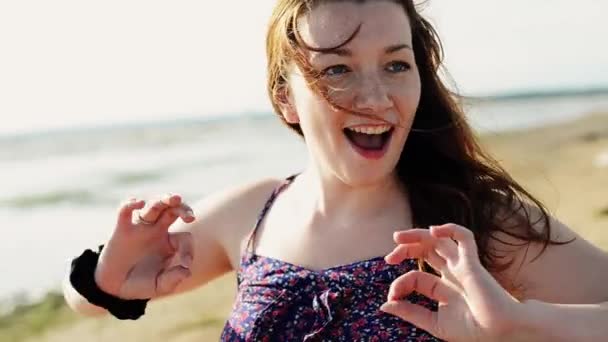 Щаслива молода дівчина танцює на пляжі посмішка в камері. Сонячний день. Чоловік на велосипеді . — стокове відео