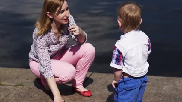 Mutter spricht mit kleinem Sohn in blauer Hose am Meer. Veranstaltung. Sommer. Wasser. — Stockvideo