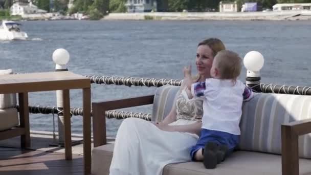 Anya, a kis fia, a kanapé, a tengerparti jelentő. csók. Terasz-étterem. — Stock videók