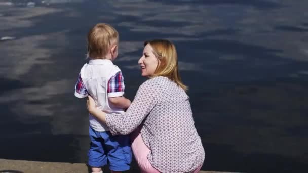 Mor med lille son tittar på vatten vid havet. Händelse. Solig sommardag. — Stockvideo
