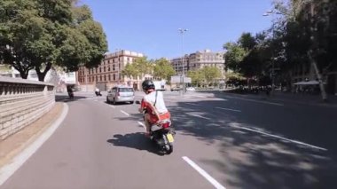 Barselona, İspanya - 7 Haziran 2015: Kasklı insanların arka yüzü şehirde yolda scooter'lara biniyor. Insanlar. Mimari. Araba. Güneşli