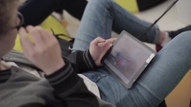 Saint Petersburg, Rusya - 16 Temmuz 2015: Genç adam yaz festivalinde elinde tabletle beanbag'ın üzerinde oturacak. Güneşli bir gün. Eğlence