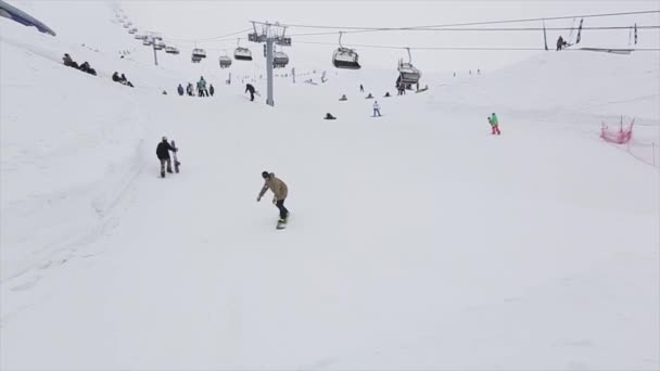 Sochi, Rusko-29. březen 2016: snowboardista na odrazový můstek v lyžařském středisku v horách. Extrémní kaskadéra. Lyžařské vleky. Lidé — Stock video