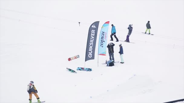 SOCHI, RUSSIA - 29 MARZO 2016: Salto dello snowboarder dal trampolino, tocco bordo tavola. Montagne innevate. Bandiere. Concorso. Persone . — Video Stock