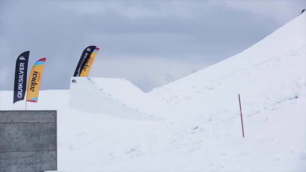 Sotschi, Russland - 29. März 2016: Skifahrer in Uniform springen vom Sprungbrett, machen einen extremen Stunt. Schneebedeckte Berge. grauer Himmel. Landschaft — Stockvideo