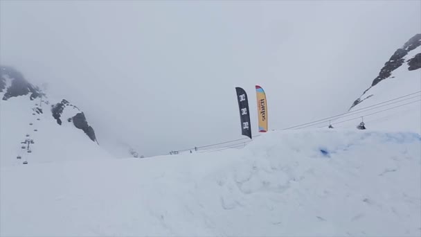 СОЧИ, РОССИЯ - 29 марта 2016 года: Лыжник прыгает в высоту с трамплина на склоне. Горнолыжный курорт в снежных горах. Вызов. Флаги — стоковое видео