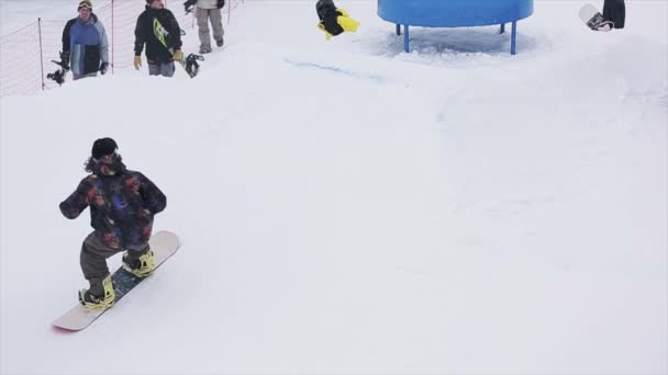 SOCHI, RUSIA - 29 DE MARZO DE 2016: Snowboarder saltar en patada, voltear en el aire en la estación de esquí. Montañas nevadas. Deporte extremo. Gente . — Vídeos de Stock