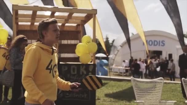 СЕНТ-ПЕТЕРБУРГ, РОССИЯ - 16 июля 2015 года: Человек в желтой толстовке играет в теннис на летнем фестивале. Размахиваю флагами. Людей. Развлечения Солнечный день — стоковое видео