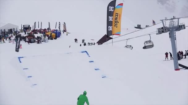 Сочі, Росія-29 березня 2016: сноубордист в шолом стрибати з трампліна на гірськолижному курорті Grab борту в повітрі. Снігові гори. Людей — стокове відео