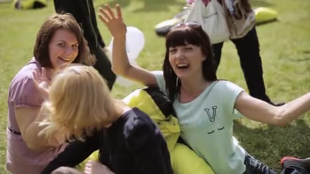 SAINT PETERSBURG, RUSSIA - 16 LUGLIO 2015: Tre donne felici siedono sui sacchetti di fagioli e posano sulla macchina fotografica. Mani d'onda. Festival estivo. Spettacolo . — Video Stock