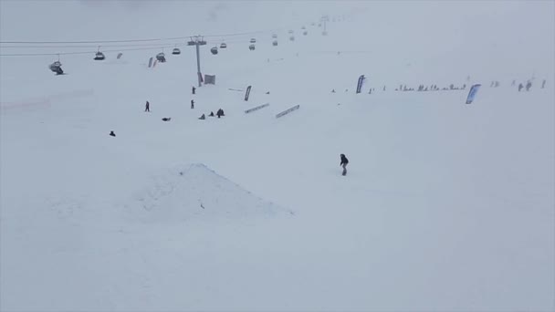 SOCHI, RUSSIE - 29 MARS 2016 : Snowboarder jump from springboard at slope, touch board in air. Station de ski dans les montagnes enneigées . — Video