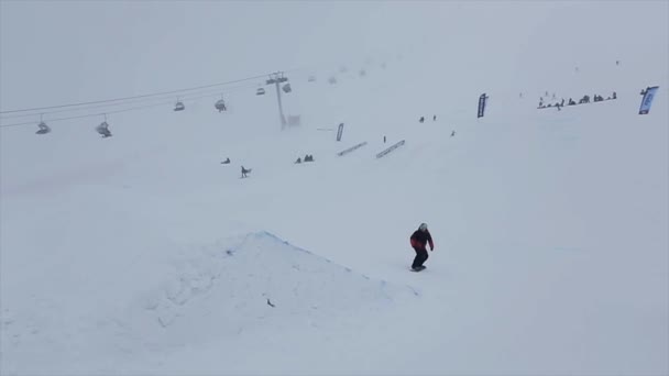 Sochi, Oroszország - március 29, 2016: Snowboardos ugrás az ugródeszka a lejtőn, 360, megragad tábla megfordítása a levegőben. Sípálya-hegység. — Stock videók