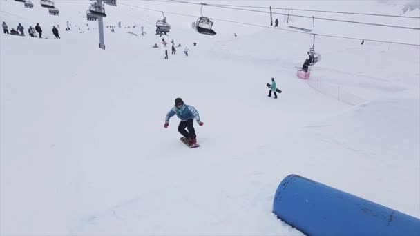 SOCHI, RUSIA - 29 DE MARZO DE 2016: Salto snowboarder sobre trampolín en pendiente en las montañas. Truco extremo. Desafío. Gente. Estación de esquí — Vídeos de Stock