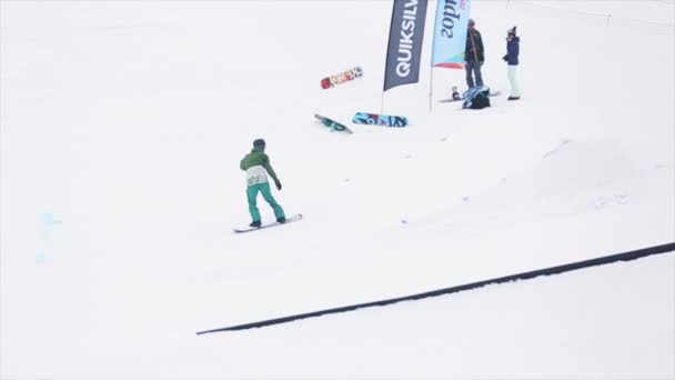 SOCHI, RUSSIA - 29 marzo 2016: Salto dello snowboarder dal trampolino di lancio. Montagne innevate. Bandiere. Concorso. Gente. Sport estremi. Sciatori — Video Stock