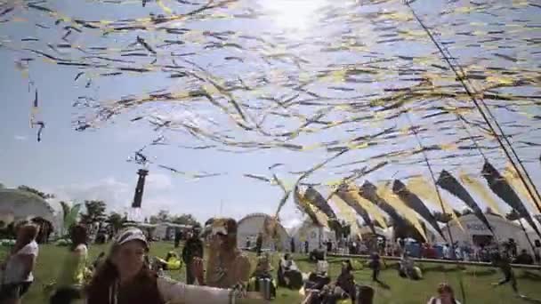 САЙНТ-ПЕТЕРБУРГ, РОССИЯ - 16 июля 2015 года: размахивают желтыми и черными лентами на летнем фестивале. Подростки в масках. Люди на мешках с бобами. Развлечения — стоковое видео