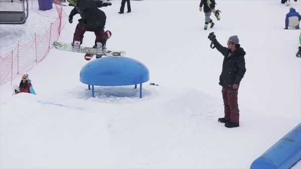 Sochi, Rusko-29. březen 2016: snowboardista skáčou na vystřelovač. Zasněžené hory. Extrémní sport. Lidé. Kameraman. Lyžařské středisko — Stock video