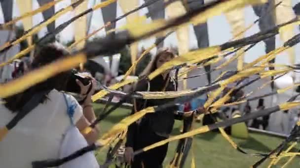 상트 페테르부르크, 러시아 - 7 월 16, 2015 : 여름 축제에 검은 색과 노란색 테이프를 흔들며 여자 촬영 친구. 미소. 엔터테인먼트. — 비디오