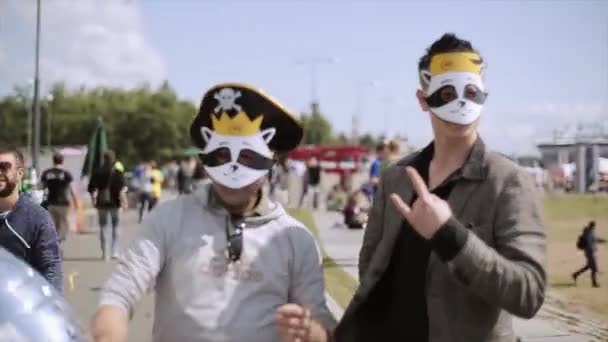 Санкт-Петербург, Росія-16 липня 2015: двоє молодих людей в смішні маски постановки на камеру з кришталевою повітряної кулі. Літній фестиваль. Сонячний день — стокове відео