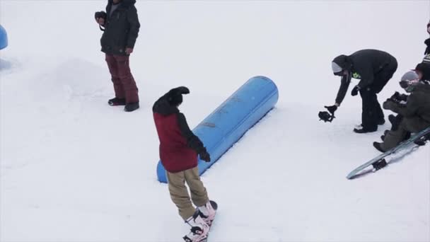 Soczi, Rosja-29 marca, 2016: Snowboarder slajdów na niebieskim kicker w ośrodku narciarskim. Śnieżne góry. Sport ekstremalny. Kamerzysta. Akrobacje — Wideo stockowe