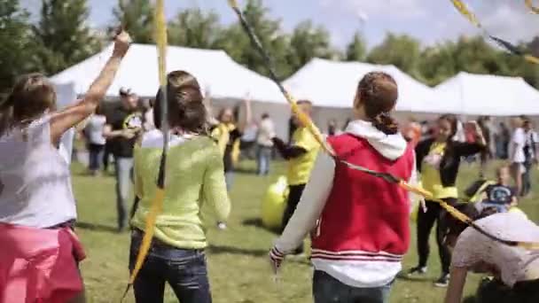 SAINT PETERSBURG, RÚSSIA - 16 de julho de 2015: Parte de trás das pessoas que dançam no festival de verão no parque verde. Acenando fitas pretas e amarelas. Ensolarado . — Vídeo de Stock