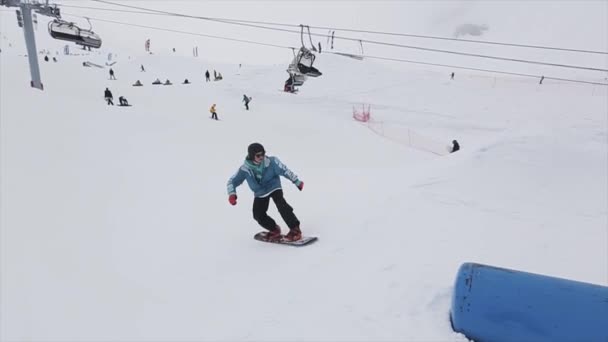 SOCHI, RUSIA - 29 DE MARZO DE 2016: Deslizamiento de snowboarder sobre trampolín en estación de esquí de montaña. Truco extremo. Camarógrafo. Gente — Vídeos de Stock