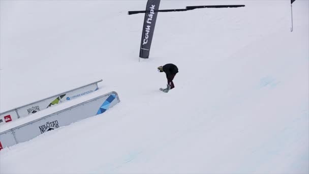 Sochi, Oroszország-március 29, 2016: Snowboarder csúszik a vasútvonalon a lejtőn a sípálya, tartsuk lenyomva a fedélzeten. Havas hegyek. Emberek — Stock videók